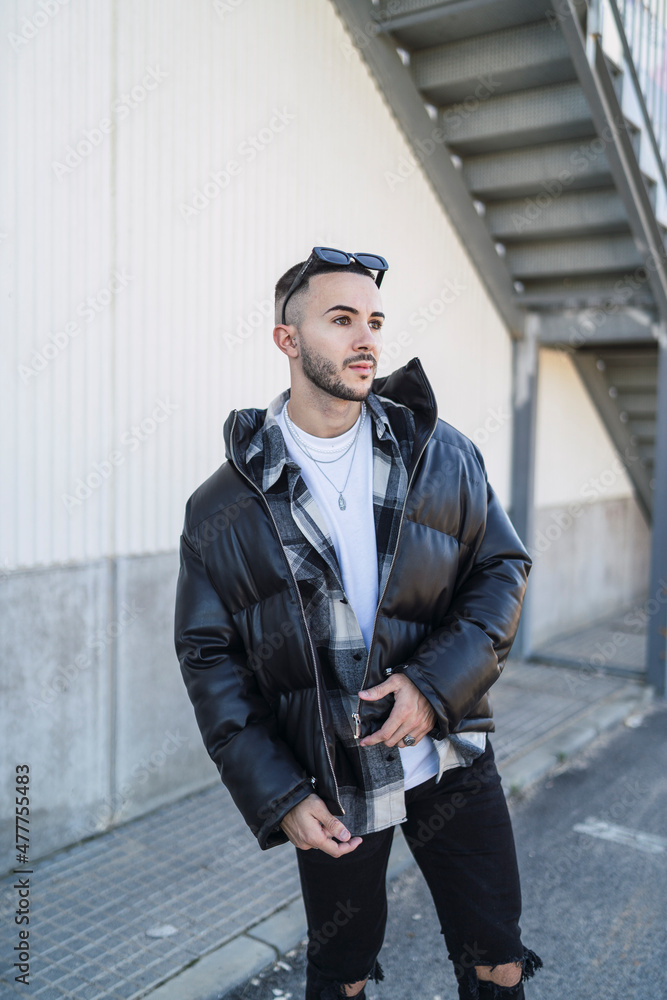 Chico joven tatuado posando con ropa urbana en la calle Chico joven tatuado posando con ropa urbana en la calle