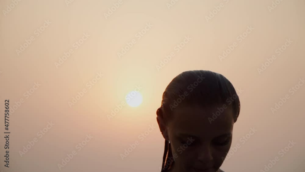 Caucasian girl bathes in the sea against the backdrop of the sunset. Slim European woman in a swimsuit smiles and swims in the ocean in the evening. Pink sky. Caucasian girl bathes in the sea against the backdrop of the sunset. Slim European woman in a swimsuit smiles and swims in the ocean in the evening. Pink sky.