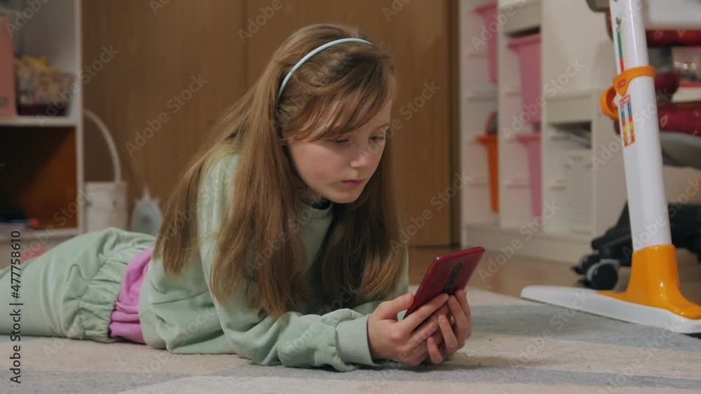Girl with a phone lying on the floor home indoors Girl with a phone lying on the floor home indoors
