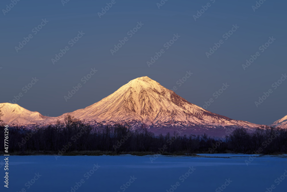 Snow-capped mountain in the evening light of the setting sun. Hill, winter landscape.