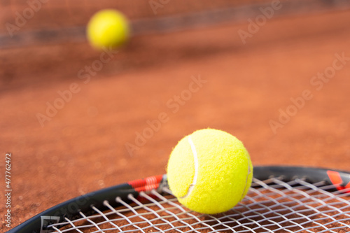 Tennis yellow ball on racket lying on clay court. Sports tournament competition concept