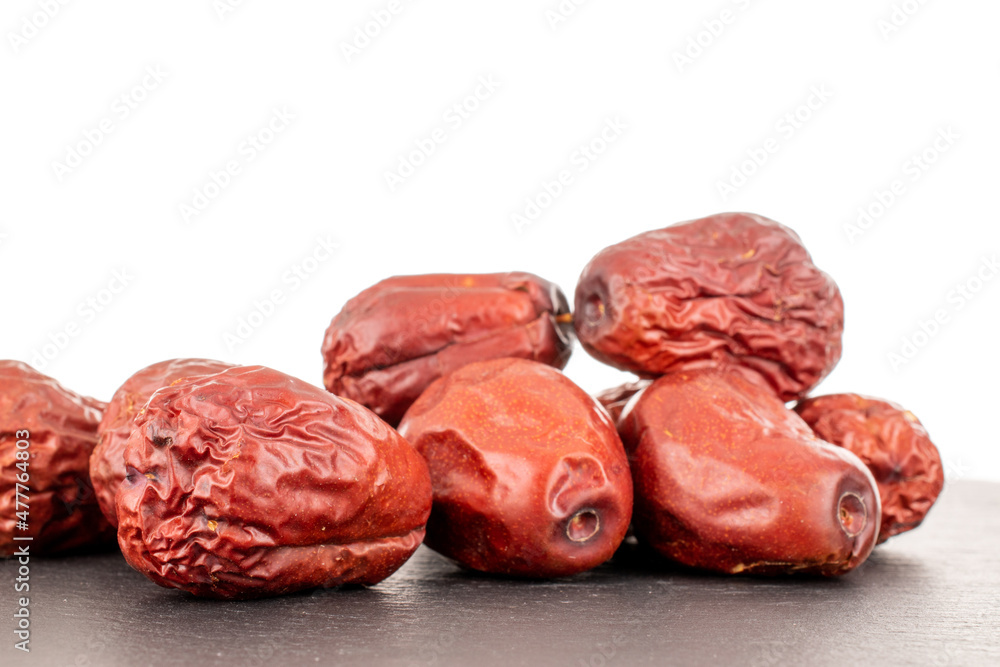 Several sweet dried ziziphus berries on a slate stone, close-up, isolated on white. Several sweet dried ziziphus berries on a slate stone, close-up, isolated on white.