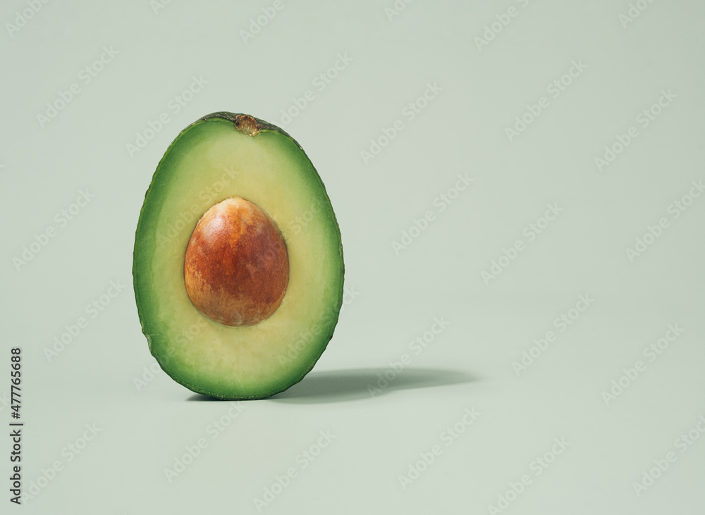 Avocado half macro shot isolated on a pastel green background. Fresh ingredients minimal concept.