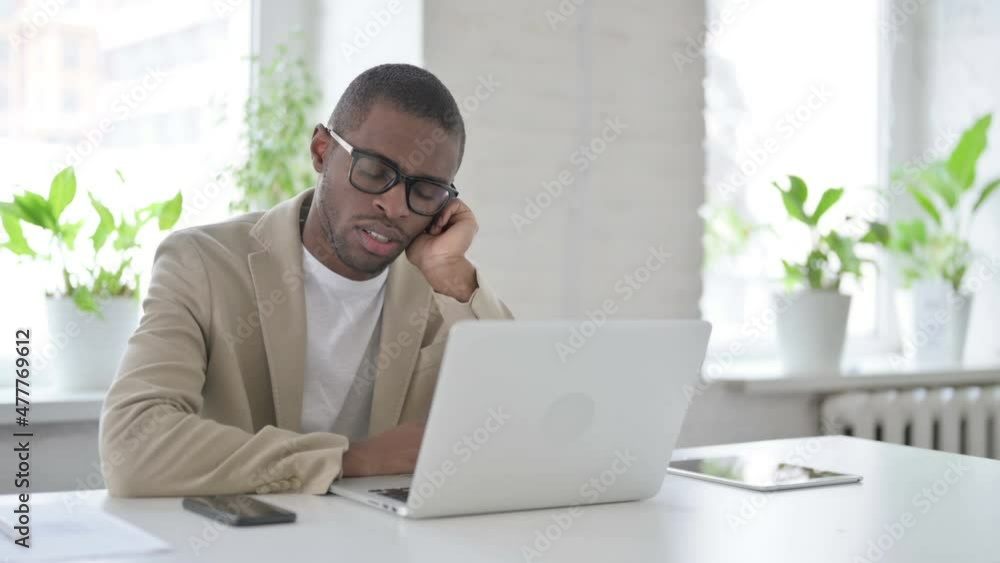Tired African Man taking Nap While Sitting in Office with Laptop Tired African Man taking Nap While Sitting in Office with Laptop