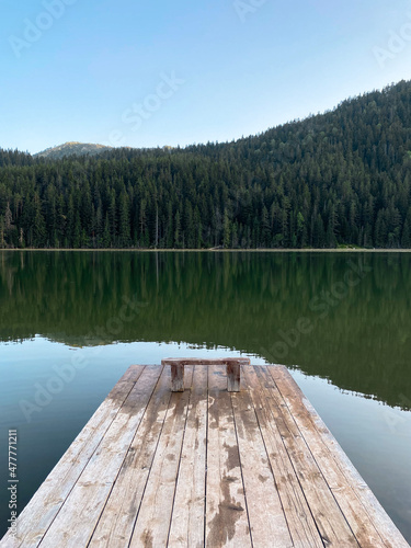Wooden feast on a mountain lake with a view of the mountains and forest, perspective, beautiful landscape