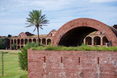 Large parade powder magazine in Fort Jefferson at Dry Tortugas National Park, Florida Keys. Gunrooms known as casemates, form a honeycomb of brick masonry arches. Palm tree and parade grounds. photo