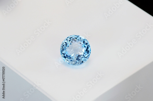 Checker faceted sky blue natural topaz round gemstone setting. Color enhanced using classic irradiation as a treatment method. Transparent sparkling colorful and clean gem in white box background.