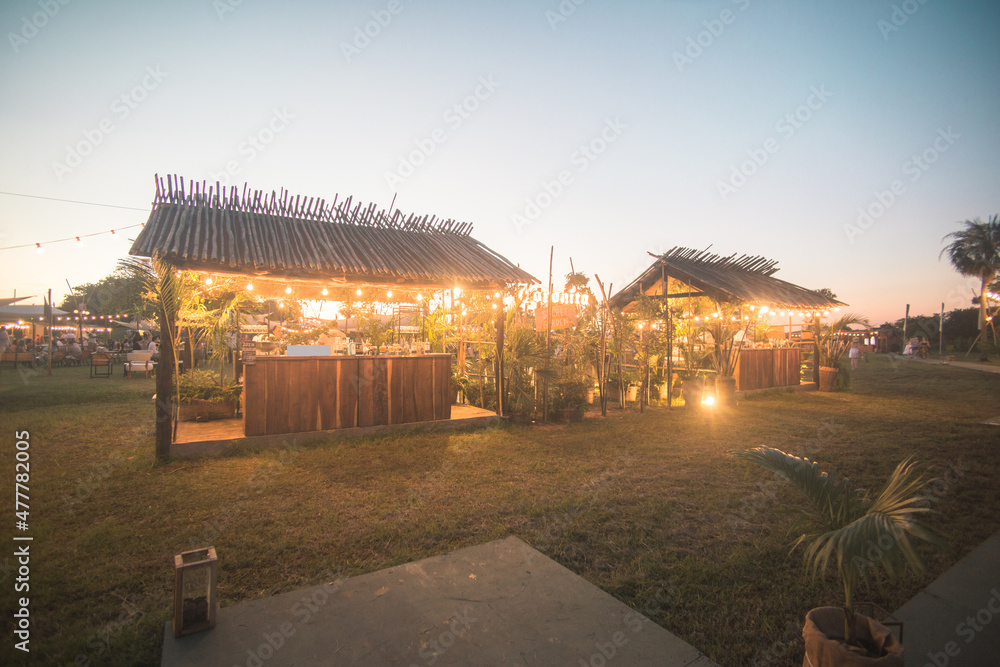 Casas de madera y mimbre natural con jardines iluminados en el atardecer Casas de madera y mimbre natural con jardines iluminados en el atardecer