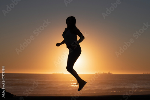 silhouette of woman jumping on the beach at sunset