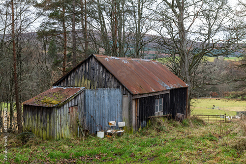 Fototapet BALLINDALLOCH, MORAY, SCOTLAND - 30 DECEMBER 2021: This is a a very old wooden building used for storage in Ballindalloch, Moray, Scotland on 30 December 2021