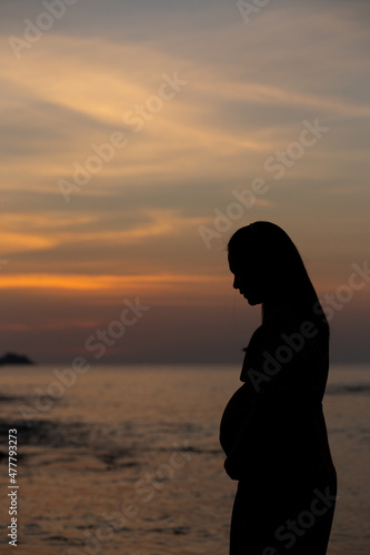 silhouette of a person sitting on a bench, sunset over the river, Patong beach © Pattarakrich