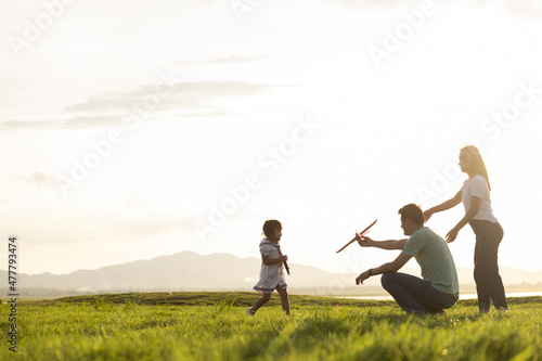 Asian children playing cardboard airplane together in the park outdoors