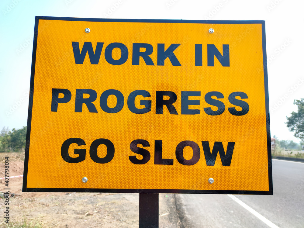 work in progress go slow sign board at road construction site work in progress go slow sign board at road construction site