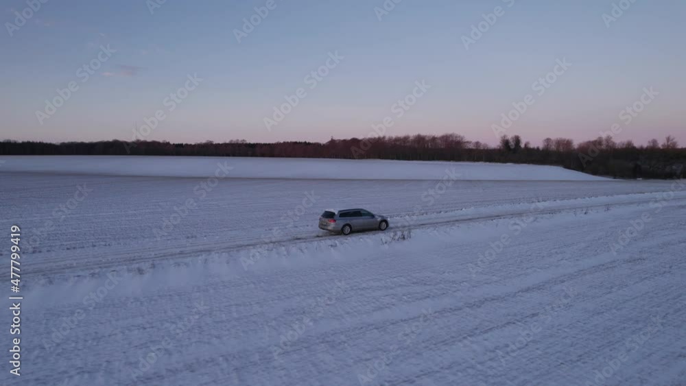 Car Drives On An Icy Snow Covered Road In Denmark, Scandinavia Drone Flying Beside A Car Driving On An Icy Road With Snow Covering The Fields With A Deep Blanket Of Snow. - Truck Shot Car Drives On An Icy Snow Covered Road In Denmark, Scandinavia Drone Flying Beside A Car Driving On An Icy Road With Snow Covering The Fields With A Deep Blanket Of Snow. - Truck Shot