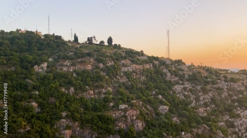 Electricity Pylons And Communication Towers On Rocky Mountain In Kaslik, Keserwan District, Lebanon With Golden Hour Sunset By The Sea Revealed. panning photo