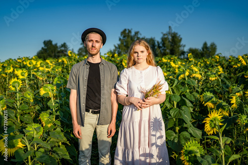 Portrait of a young village couple in a sunflower field. Girl with natural beauty with a bouquet of dried flowers