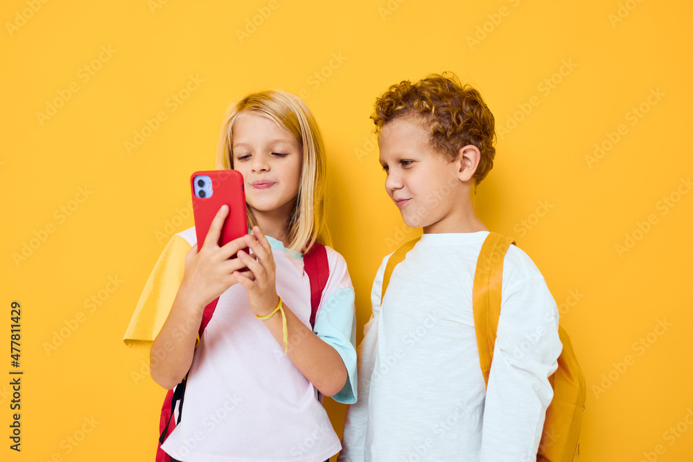 Two kids boy and girl looking at the phone entertainment communication isolated background Two kids boy and girl looking at the phone entertainment communication isolated background