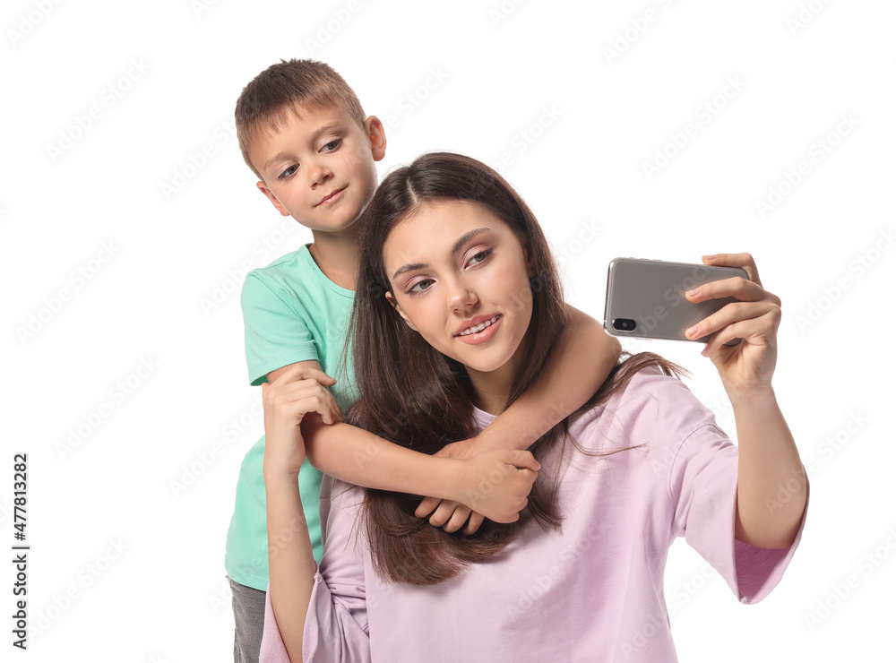 Little boy and his older sister with mobile phone taking selfie on white background Little boy and his older sister with mobile phone taking selfie on white background