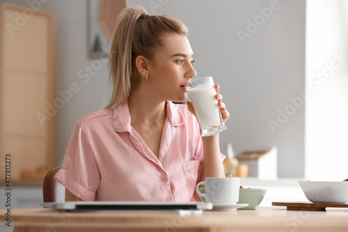 Canvastavla Pretty young woman drinking milk in kitchen