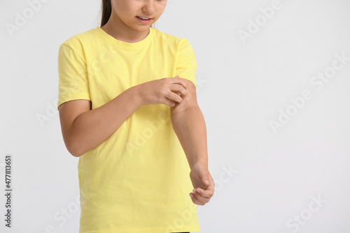 Little girl scratching herself on light background