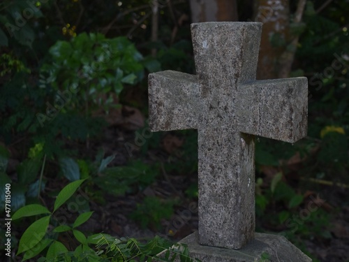 Small traditional stone cross on a grave in the forest