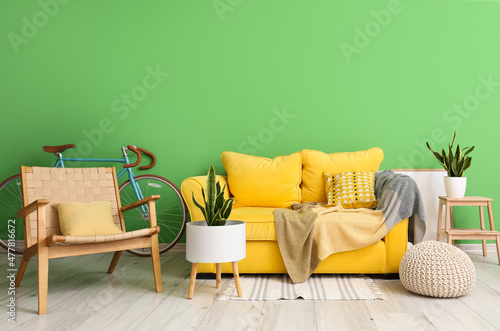 Interior of stylish living room with bicycle, sofa, armchair and green wall