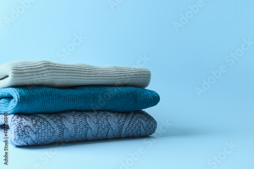Stack of warm sweaters on blue background