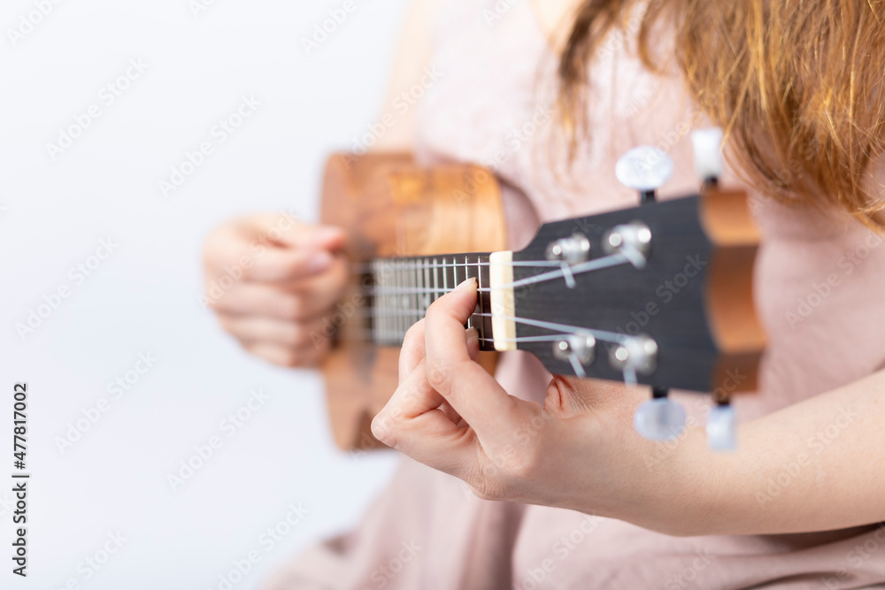 Hand of girl playing ukulele, small stringed instrument