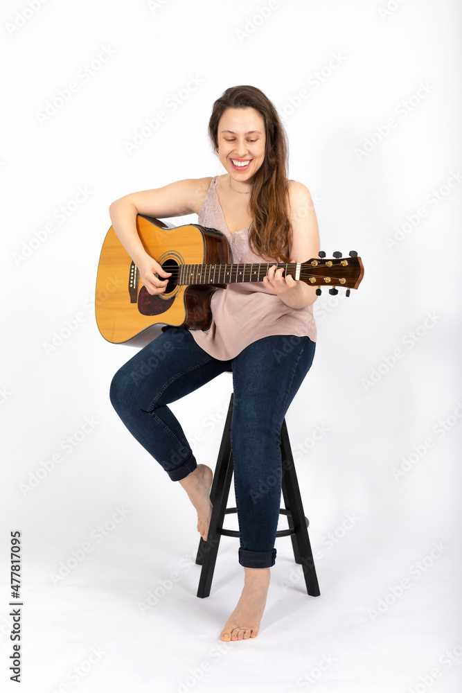 Young woman playing guitar on white background