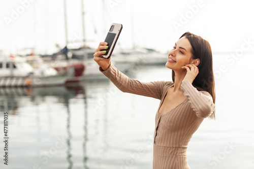 Smiling beautiful woman makes selfie in the yacht club early morning