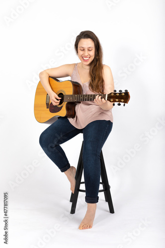 Young woman playing guitar on white background