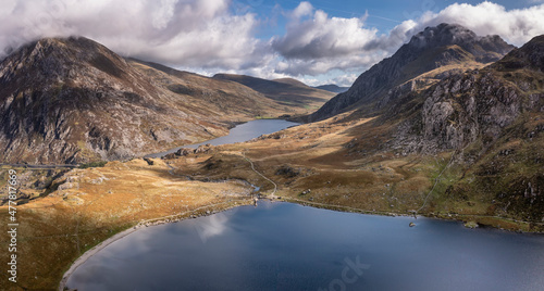 Aerial view of flying drone Epic Autumn Fall landscape image of view along Ogwen vslley in Snowdonia National Park with moody sky and mountains