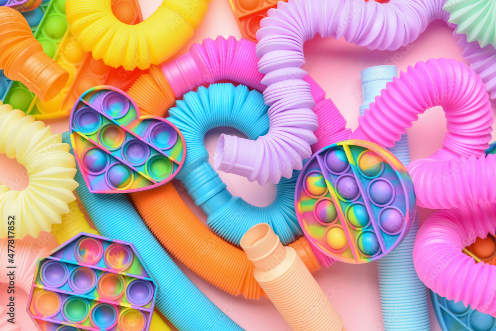 Colorful Pop Tubes and Pop it fidget toys on pink background - obrazy, fototapety, plakaty 