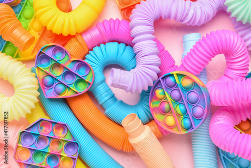 Colorful Pop Tubes and Pop it fidget toys on pink background photo