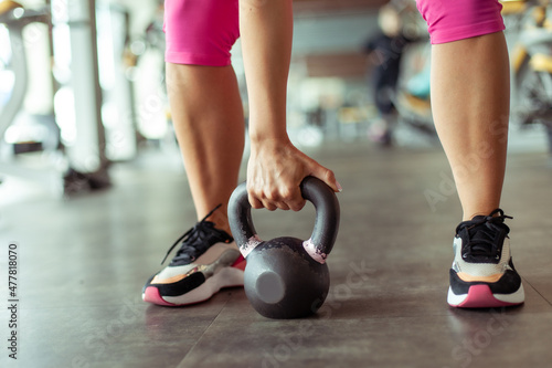 Weight training. The hand lifts the kettlebell from the floor in the gym. Woman exercising
