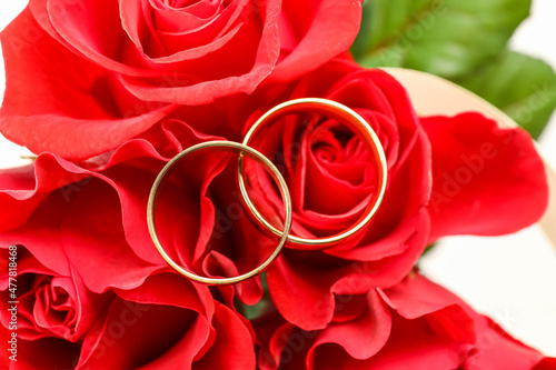 Golden wedding ring on red roses, closeup