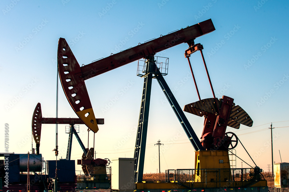Oil pumps are running in the sunset at the oil field. On the Bohai coast of China Oil pumps are running in the sunset at the oil field. On the Bohai coast of China