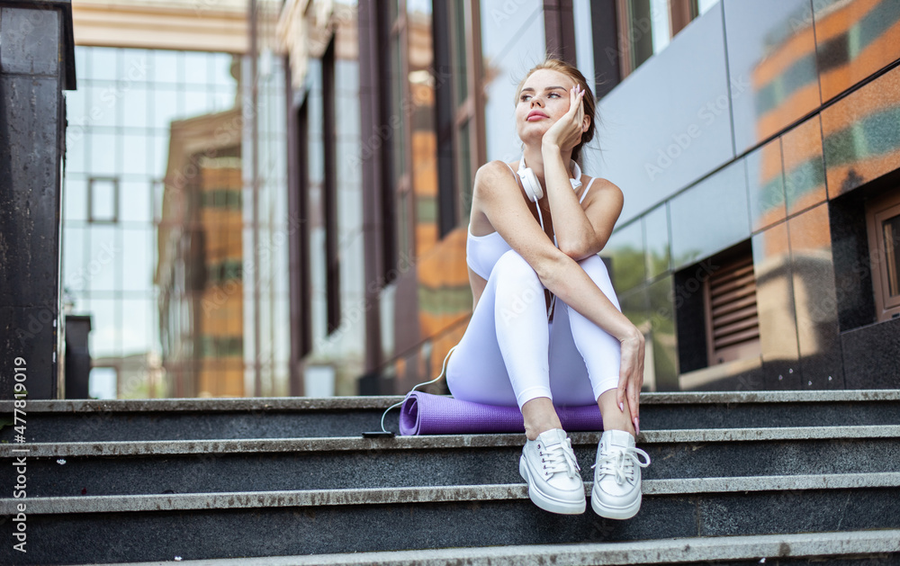 Beautiful fit woman sitting on stairs in urban environment Beautiful fit woman sitting on stairs in urban environment