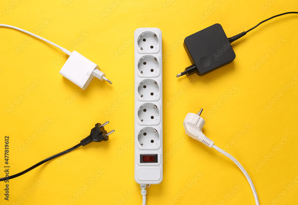 Electrical Extension cord with different plugs and adapters on yellow background. Top view. Electrical Extension cord with different plugs and adapters on yellow background. Top view.