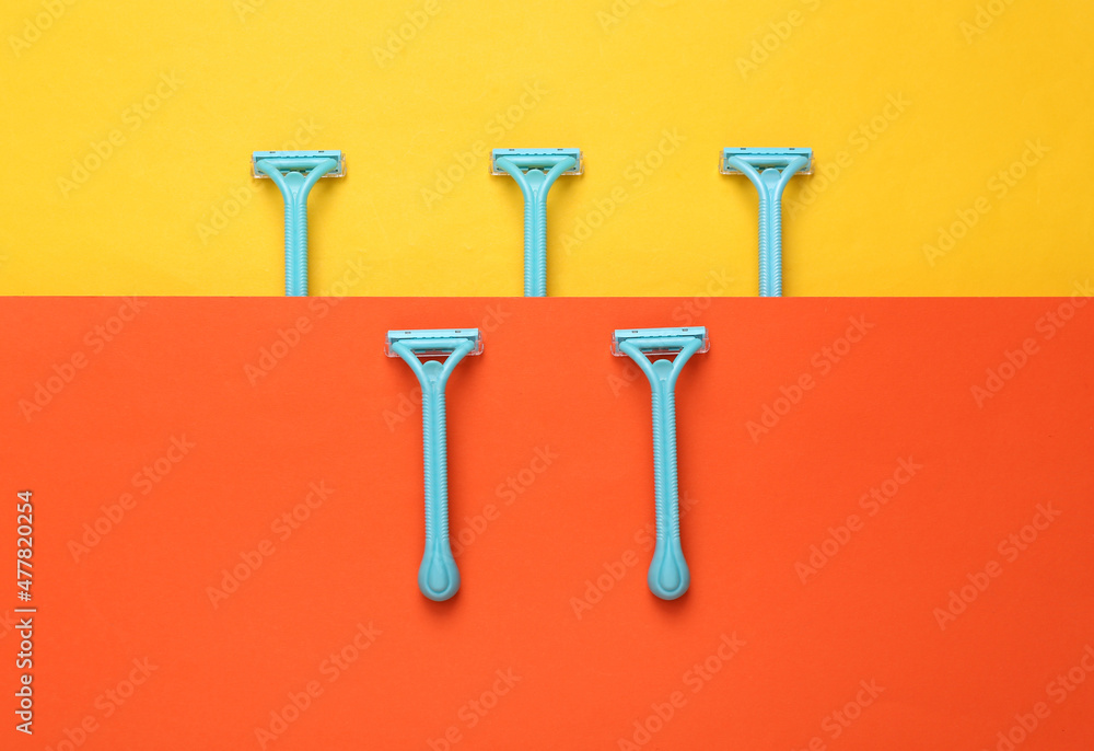 Set of disposable razors for depilation on yellow orange background. Top view Set of disposable razors for depilation on yellow orange background. Top view