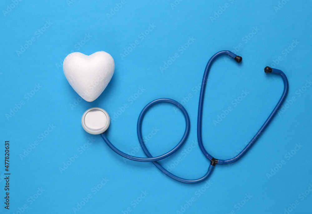 Fototapeta premium Stethoscope with hearts on blue background. Medicine, love concept