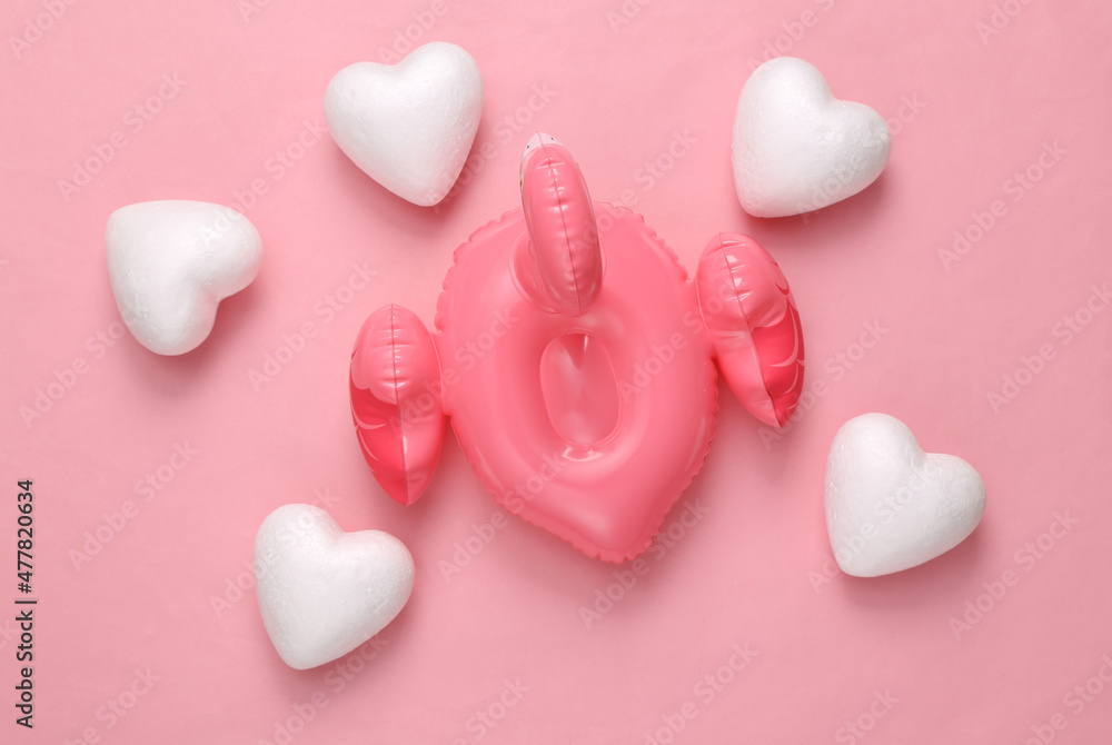 Inflatable flamingo with hearts on pink background. Love concept, top view