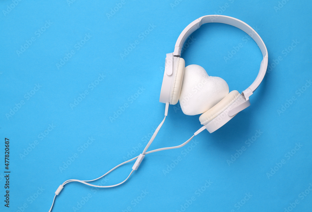 Headphones with hearts on blue background. Romantic music, love concept. Top view Headphones with hearts on blue background. Romantic music, love concept. Top view