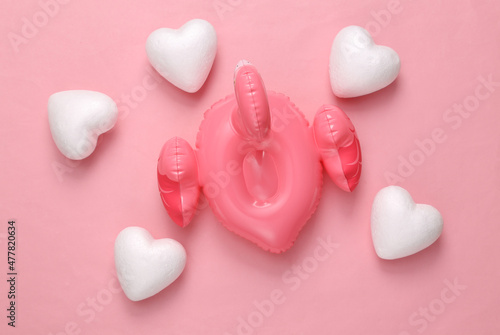 Fototapeta Naklejka Na Ścianę i Meble -  Inflatable flamingo with hearts on pink background. Love concept, top view