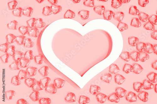 St Valentines day pink background banner. Many glass hearts around white heart frame flat lay. Love or wedding concept