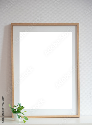 Mock up de cadre en bois sur une étagère avec une petit plante verte et mur blanc