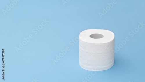 Toilet paper tissue roll on blue with copy space