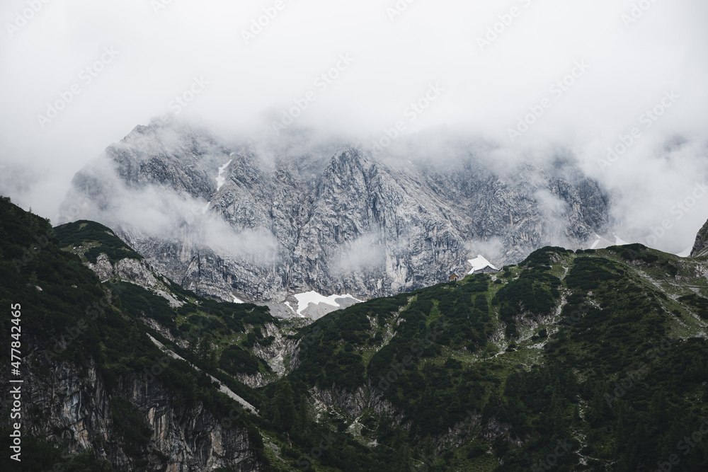 Berge mit Wolken und Gras und der Coburger Hütte in den Alpen 