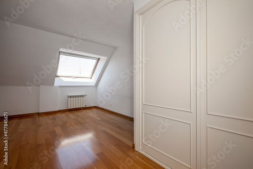 empty room with loft ceilings, window and white built-in wardrobe