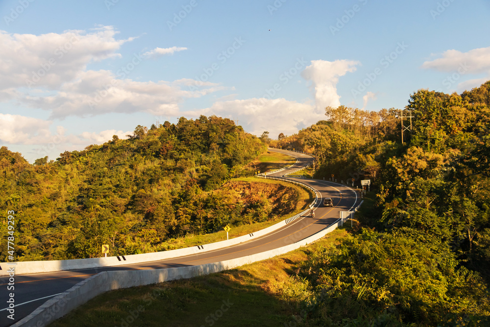Fototapeta premium Curve road No. 3, or sky road on Root 1081 over top of mountains with green jungle in Santisuk - Bo Kluea District. Beautiful landscape scenic of road number three at Nan, Thailand.